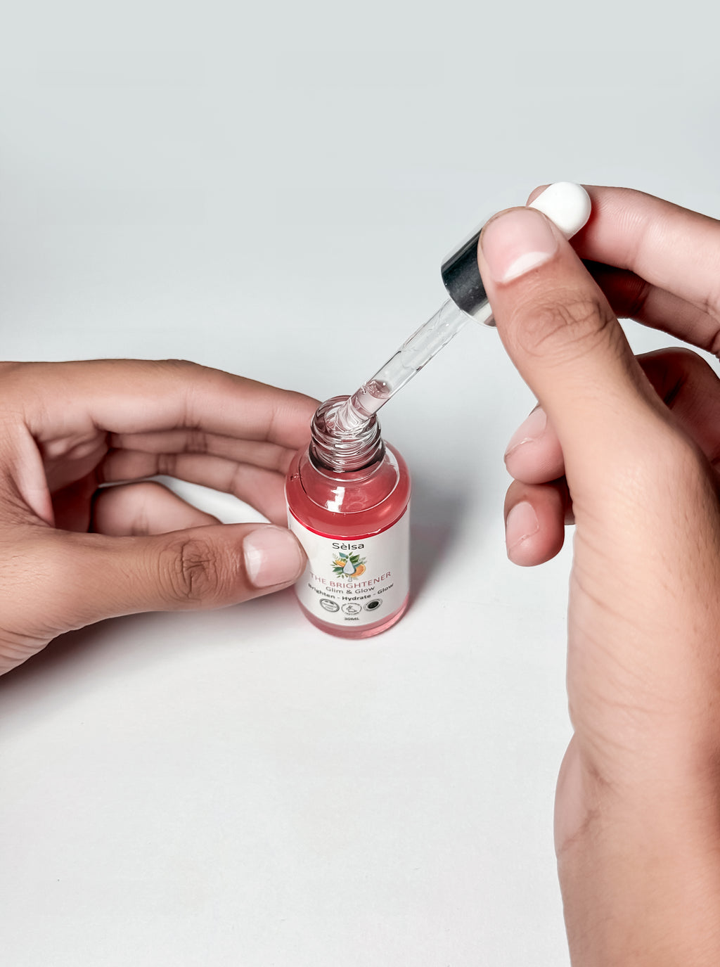 Hands holding Sèlsa Beauty Multi Vitamin Brightening Serum with Hyaluronic Acid, Niacinamide, Zinc PCA, Alpha Arbutin, and Vitamin C – multi purpose skincare dropper.